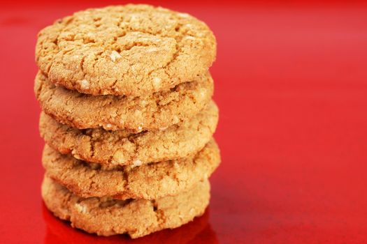 Stack of homemade peanut butter and oatmeal cookies on red enamel background