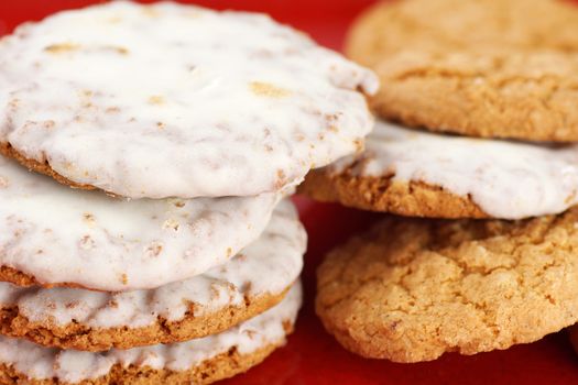 Pile of oatmeal cookies with sugar icing on red plate background