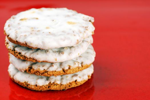 Pile of oatmeal cookies with sugar icing on red plate background