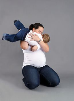 Pregnant mother playing and kissing her little boy or toddler.