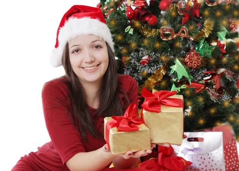 Smiling Santa girl offering gifts under Christmas tree