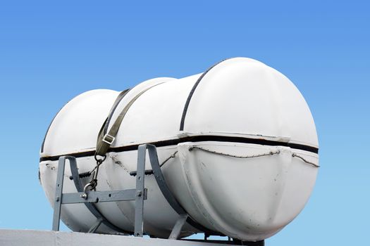 Emergency equipment: wet liferaft on large ship against blue sky