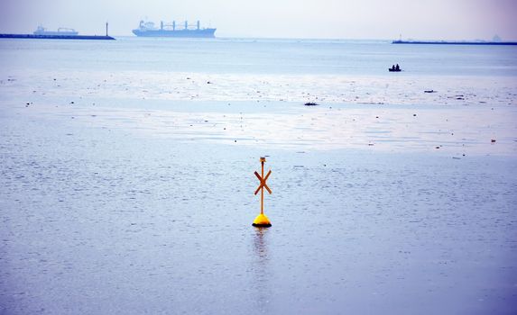 yellow buoy marker sign and boat in the ocean