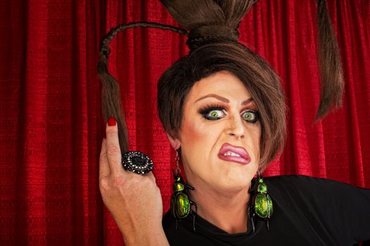 Annoyed European drag queen pulling on ponytails