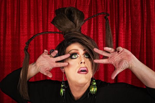 Eccentric drag queen looking up with fingers near face