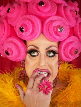 Nervous drag queen in pink wig biting nails