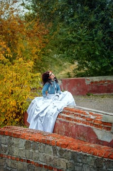 Beautiful bride in wedding dress and denim jacket in autumn park