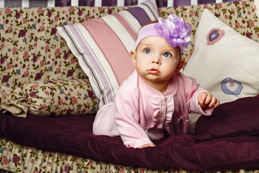 Little girl with bow on her head sitting on couch