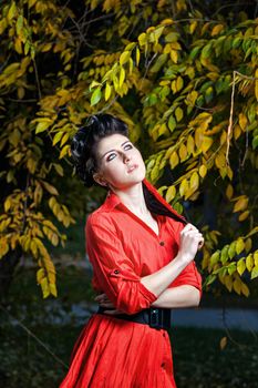 Young attractive girl in red shirt and with makeup close-up portrait in autumn park