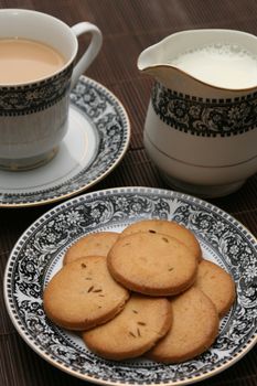 Plate full of biscuits served with milk pot and a cup of tea