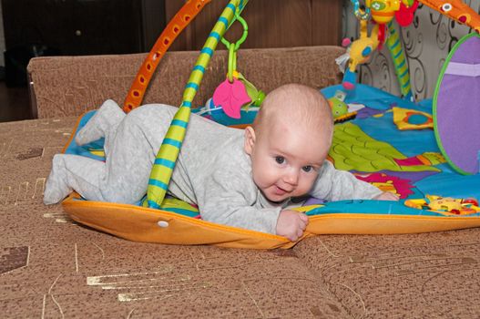 Portrait of the smiling baby creeping on a bed.