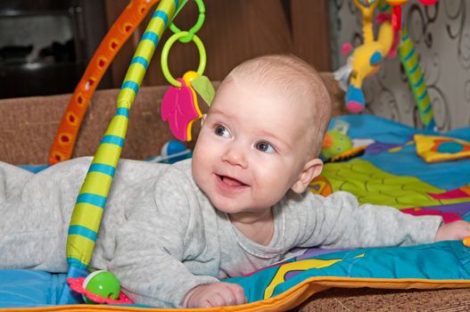 Portrait of the smiling baby creeping on a bed.