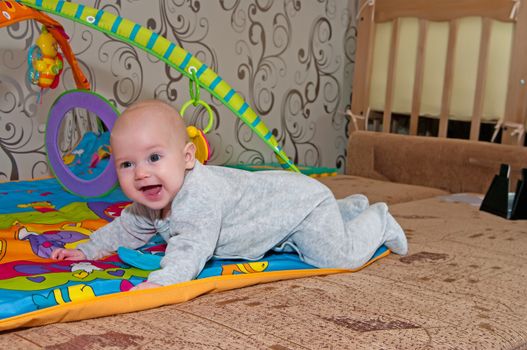 Portrait of the smiling baby crawling on a bed.