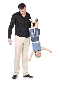 Man holds little boy upside down at white background