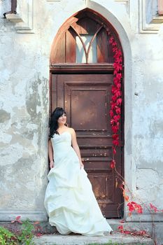 Young beautiful girl in the wedding dress near the door