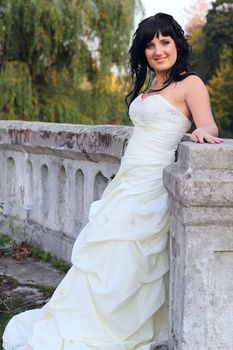 Girl in the wedding dress stands in the park