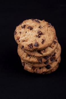 A piles of chocolate chips cookies isolated on black background.