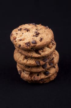 A piles of chocolate chips cookies isolated on black background.