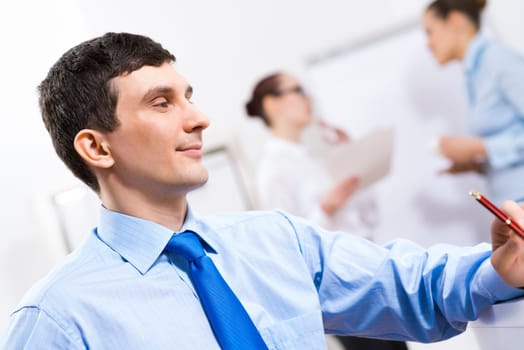 Portrait of a businessman in a blue shirt in the background of colleagues discussing