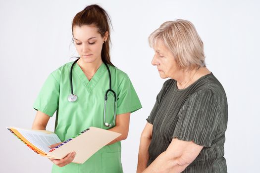Young woman nurse or doctor and senior reading medical file