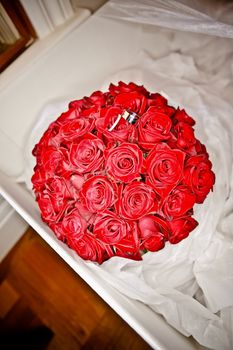 Wedding posy of beautiful fresh red roses with the rings balanced on top nestling in tissue paper