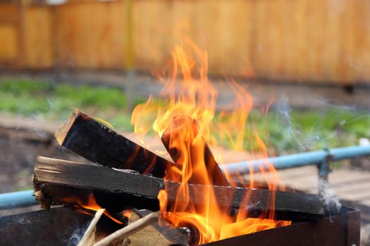 burning logs of wood piled in the grill