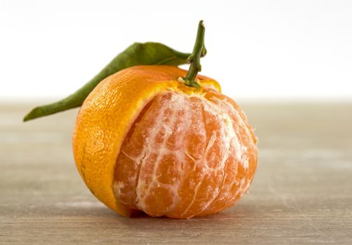 single orange mandarin with green leaves