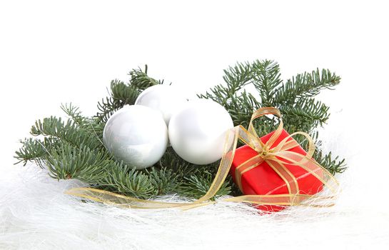 Three white Christmas balls and red present on pine tree over white background