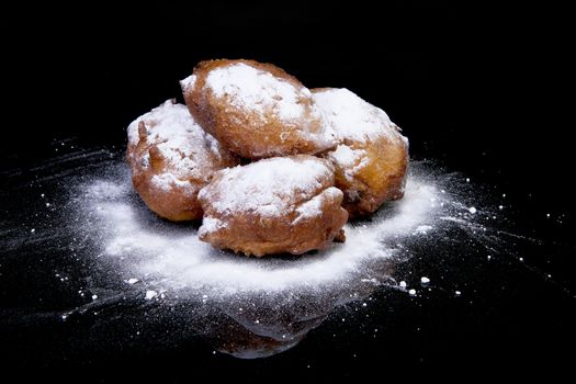Pile of Dutch donut also known as oliebollen, traditional New Year's eve food isolated over black background 