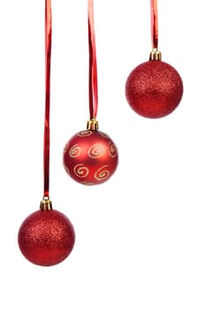 Three hanging Christmas balls on red ribbon over white background