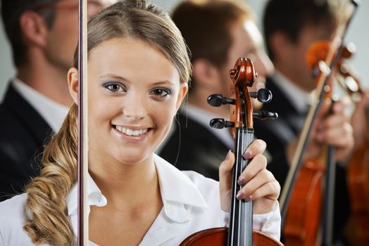 Portrait of a beautiful female violinist, musicians on background