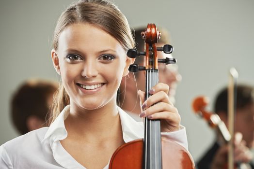 Portrait of a beautiful female violinist, musicians on background