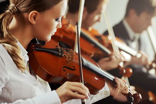 Violinists playing at the concert, young beautiful woman on foreground