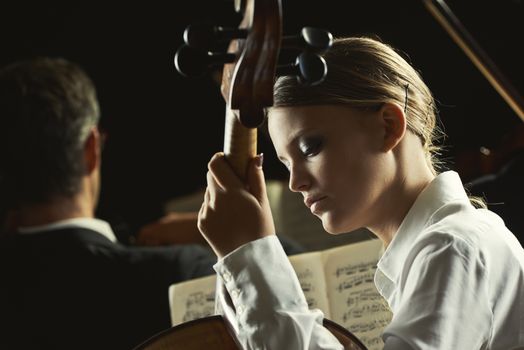 Young beautiful woman playing cello in orchestra