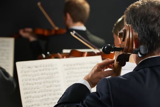 Symphony, cellist on foreground playing at the concert
