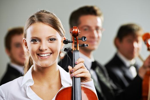 Portrait of a beautiful female violinist, musicians on background