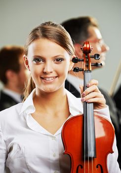 Portrait of a beautiful female violinist, musicians on background