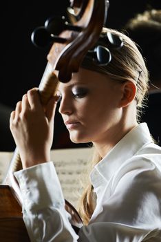 Young beautiful woman playing cello in orchestra