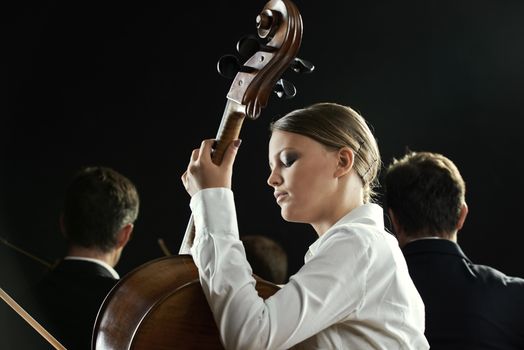 Young beautiful woman playing cello in orchestra