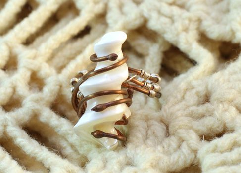 Handmade original ring of mother-of-pearl and wire on the knitted background