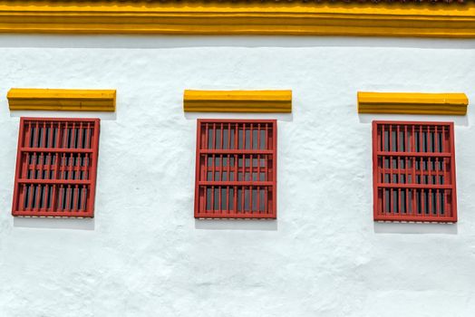 Three red windows on a white historic colonial building the center of Cartagena, Colombia