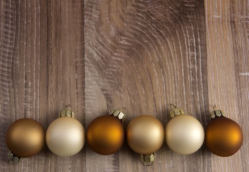 several christmas baubles bronze, brown, creme on wooden background 