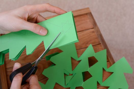 Making a chain of Christmas tree shapes from green paper