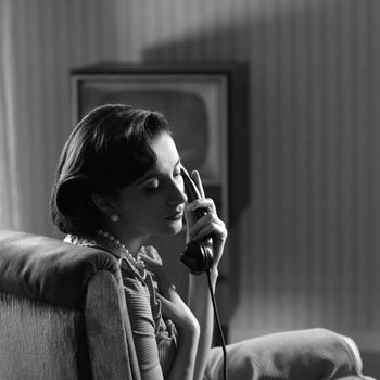 Woman talking on retro phone at home