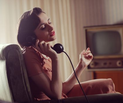 Vintage woman talking on retro phone at home