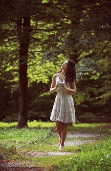 Beautiful woman  holding a vintage camera and walking on park 