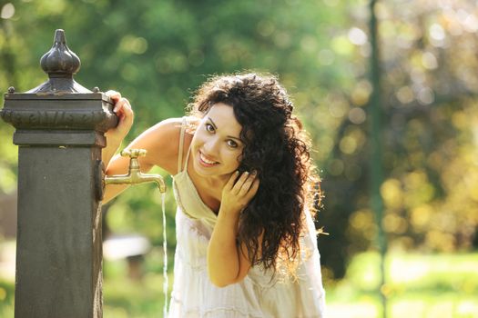 Young woman seeking refreshment from water fountain 