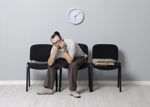 Depressed Man sitting alone in a waiting room for an appointment