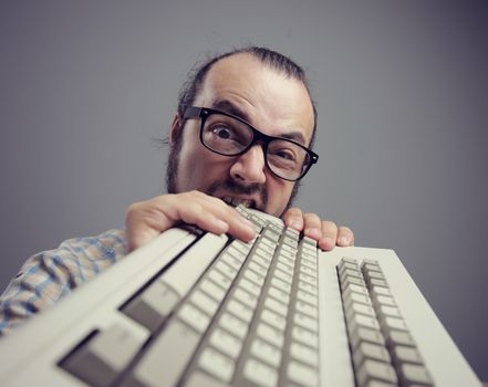 Eccentric angry man bites a keyboard