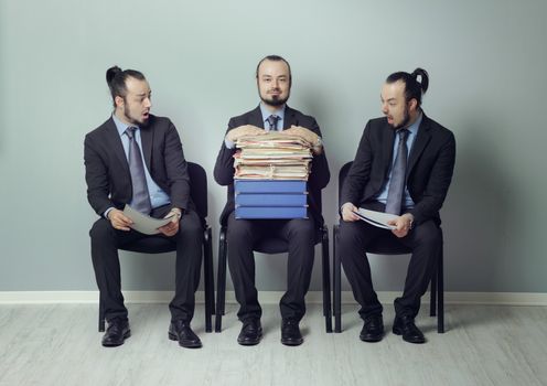 Businessman with a huge resume sitting in line with other candidates at a job interview